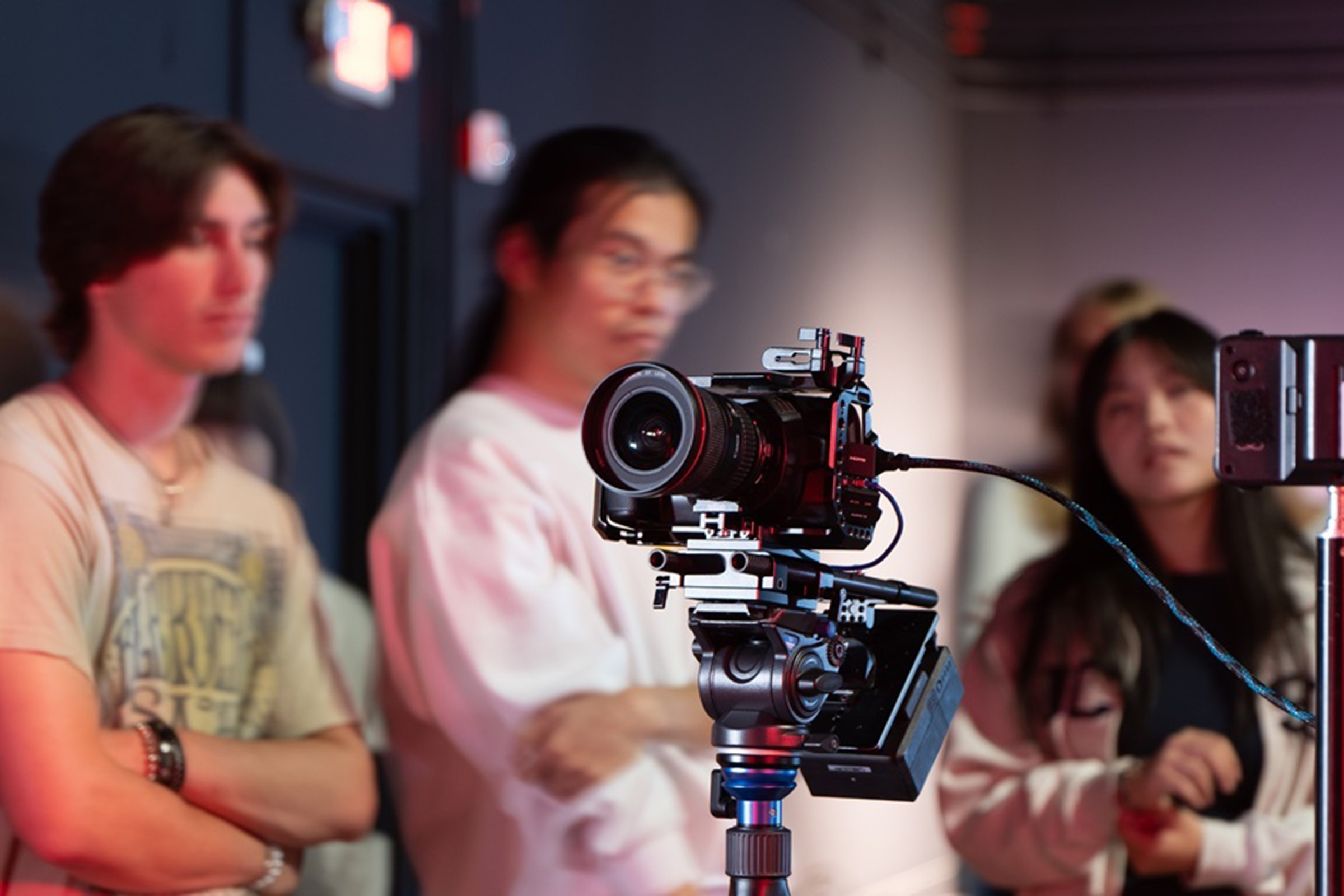 three students looking into camera equipment