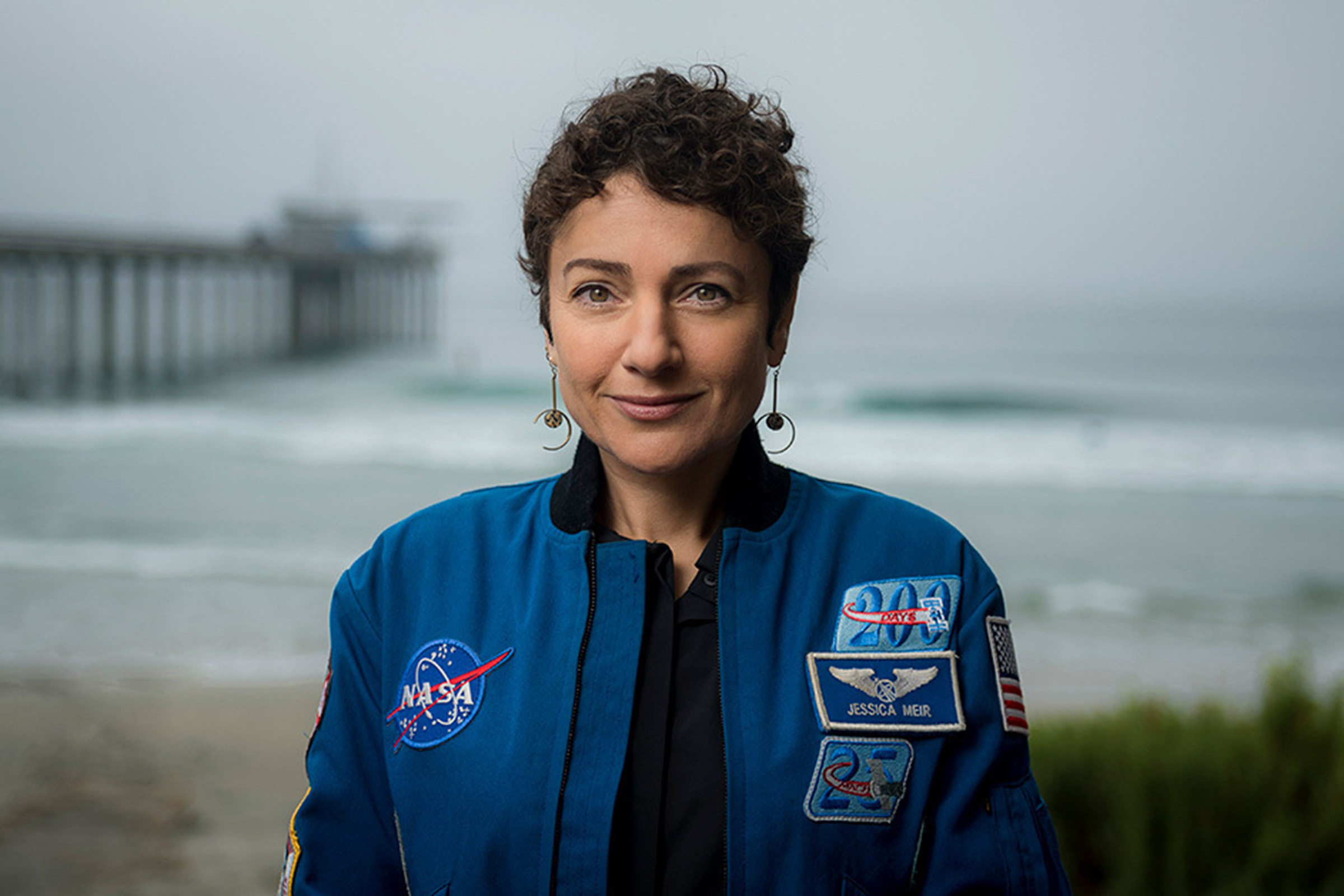 Astronaut in flight jacket in front of Scripps Pier